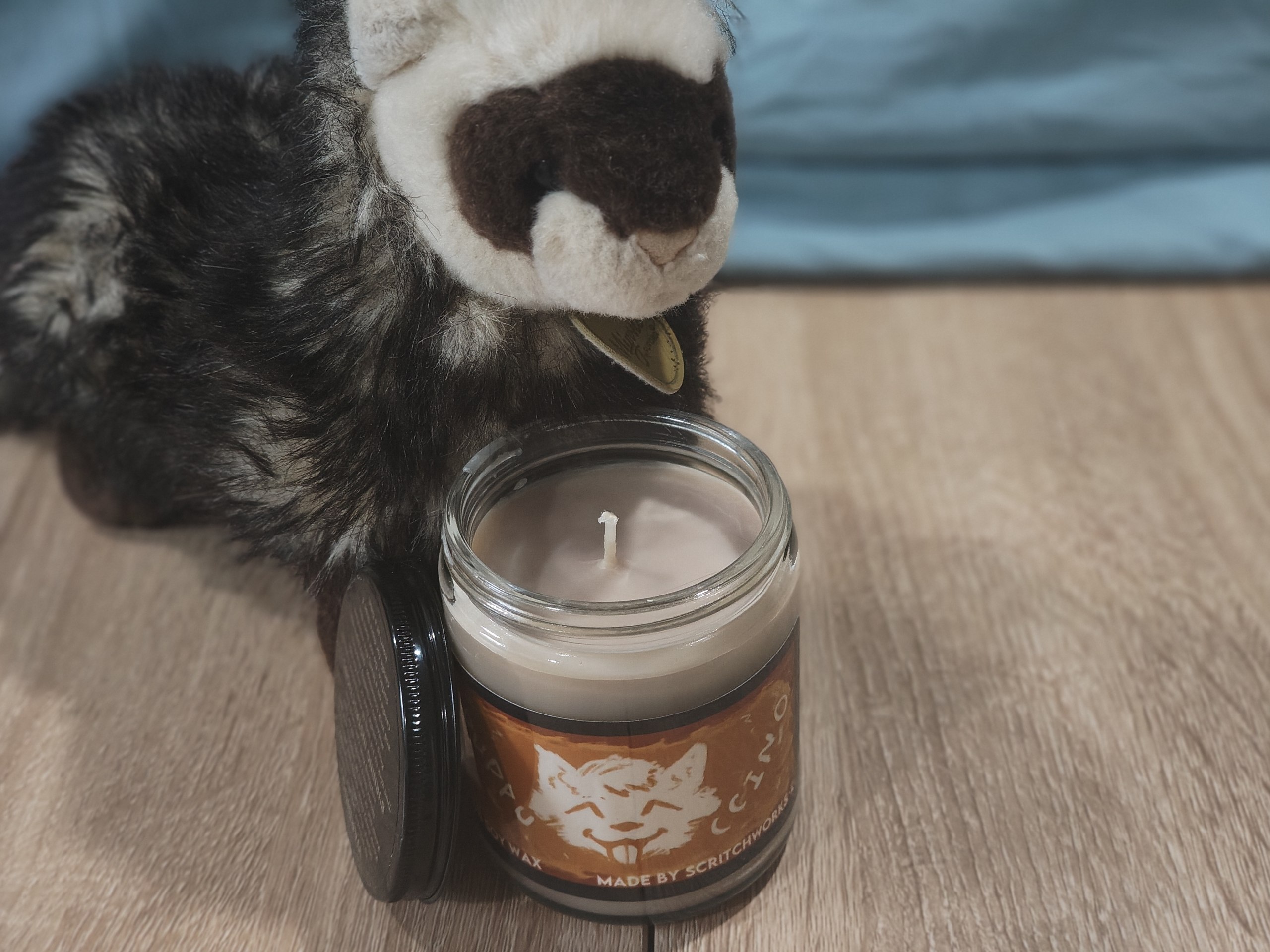 Scritch Plush sitting with a Puppuccino candle!